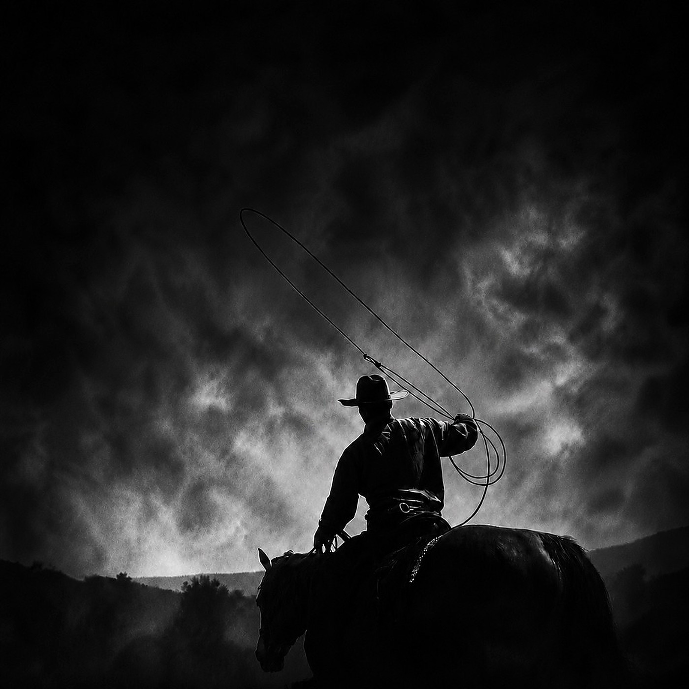 Cowboy casting a lasso against the sky